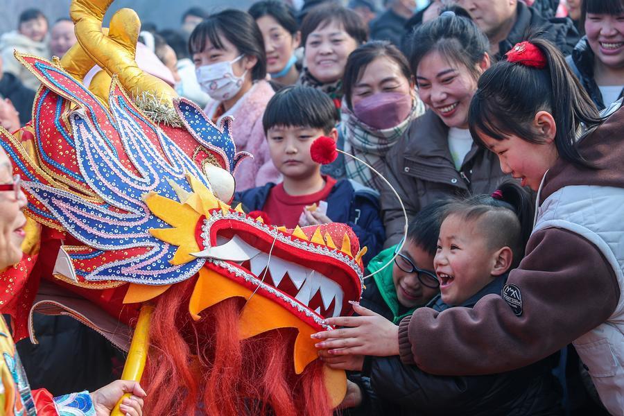 2024年2月10日，在河南商丘古城春节民俗表演巡游活动上，游客与民间舞龙队互动。 新华社发（李恒 摄）