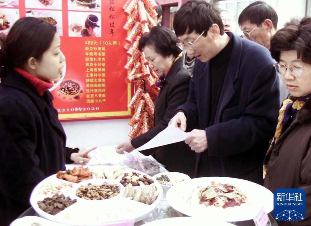 2002年2月2日，上海市民在位于南京西路休闲街区的 “年夜饭一条街 ”上选择、预订年夜饭。新华社记者 张明 摄
