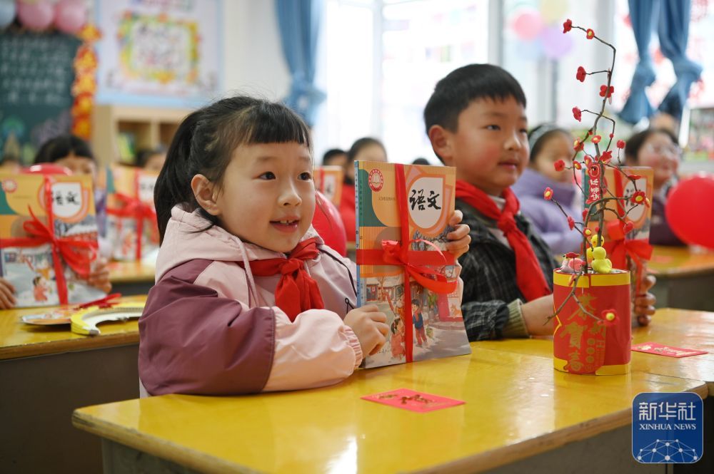 2月14日，在河南省沁阳市朱载堉学校，一年级学生展示领到的新课本。新华社发（杨帆摄）