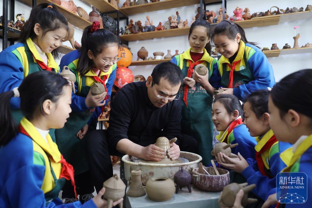2月14日，在山东省滕州市龙泉街道中心小学，老师在教学生们制作土陶。新华社发（孙杨摄）