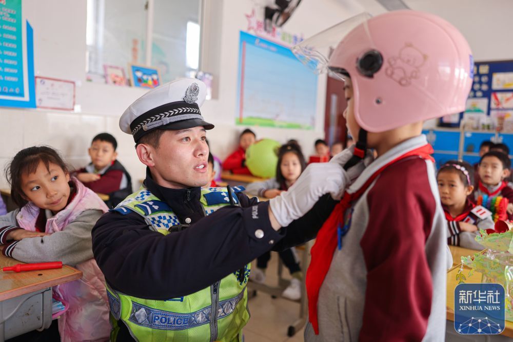 2月14日，在山东省荣成市府新小学教室内，交警为学生讲解安全头盔的正确佩戴方法。新华社发（李信君摄）
