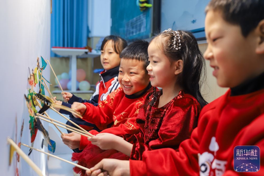 2月14日，学生在山东省青岛崇礼小学体验皮影戏表演。新华社发（张鹰摄）