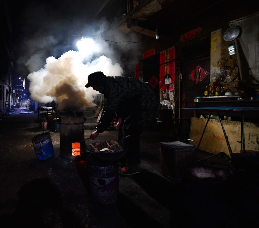 清晨，万佐成为前来做早餐的患者家属准备炭炉（2018年1月11日摄）。新华社记者 胡晨欢 摄