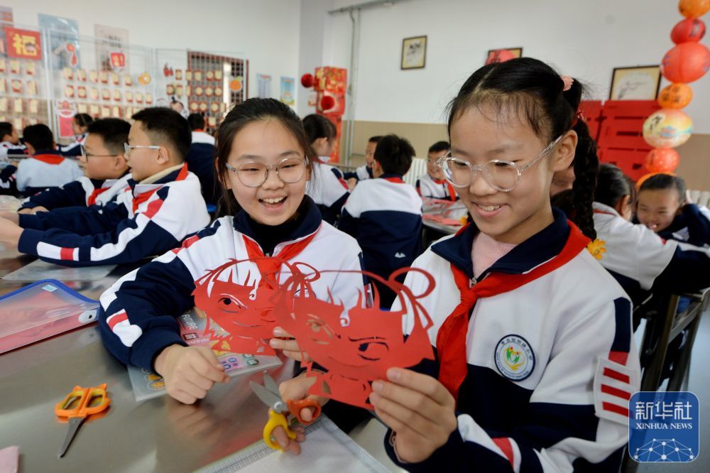 2月14日，两名学生在山东青岛宜阳路小学“传统文化润童心”主题活动中学习“哪吒”剪纸。新华社发（王海滨摄）