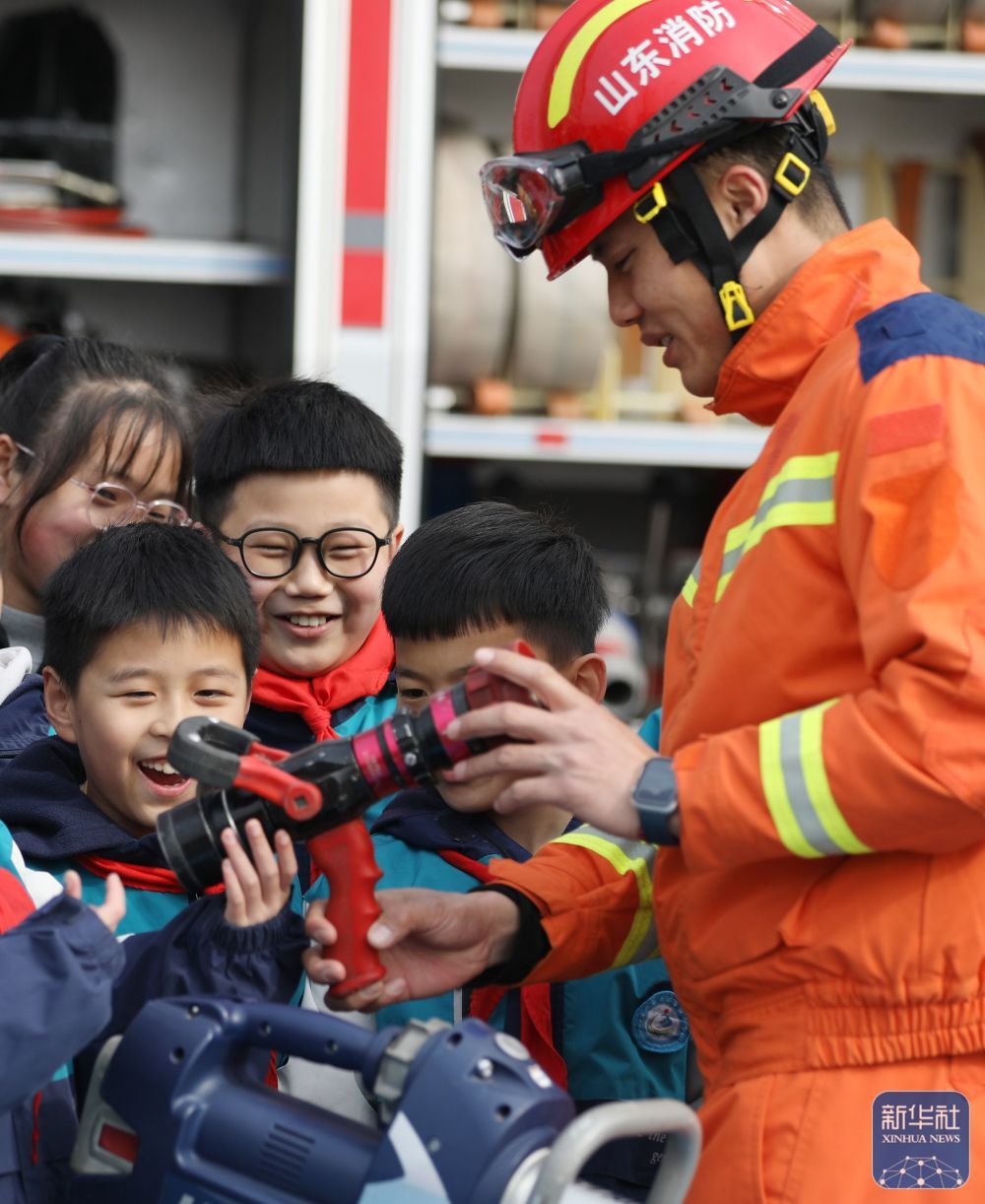 2月14日，在山东省临沂市郯城县北城实验小学，消防救援人员为小学生讲解消防装备器材。新华社发（张春雷摄）