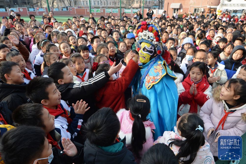 2月14日，学生们在山东青岛四方小学“传统文化润童心”主题活动中与川剧变脸演员互动。新华社发（王海滨摄）