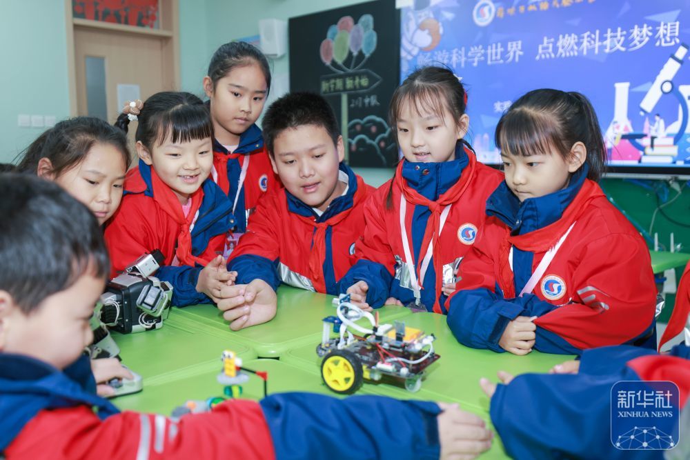 2月14日，在山东省枣庄市薛城区双语实验小学，学生们与编程机器人互动。新华社发（王龙飞摄）