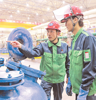 潘从明（左）在指导班组成员操作设备。本报记者 赵帅杰摄