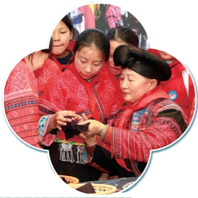 广西龙胜各族自治县龙脊镇小学，国家级非物质文化遗产代表性传承人潘继凤（右）向孩子们传授红瑶刺绣技艺。李忠波摄/光明图片